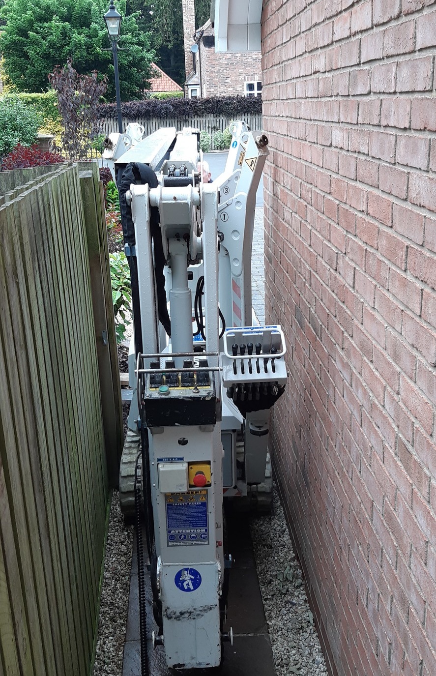 Scarlett Grace, 13m Lithium hybrid tracked spiderlift cherrypicker from High Reaching Solutions, going through narrow alleyway for building maintenance near Malton, North Yorkshire