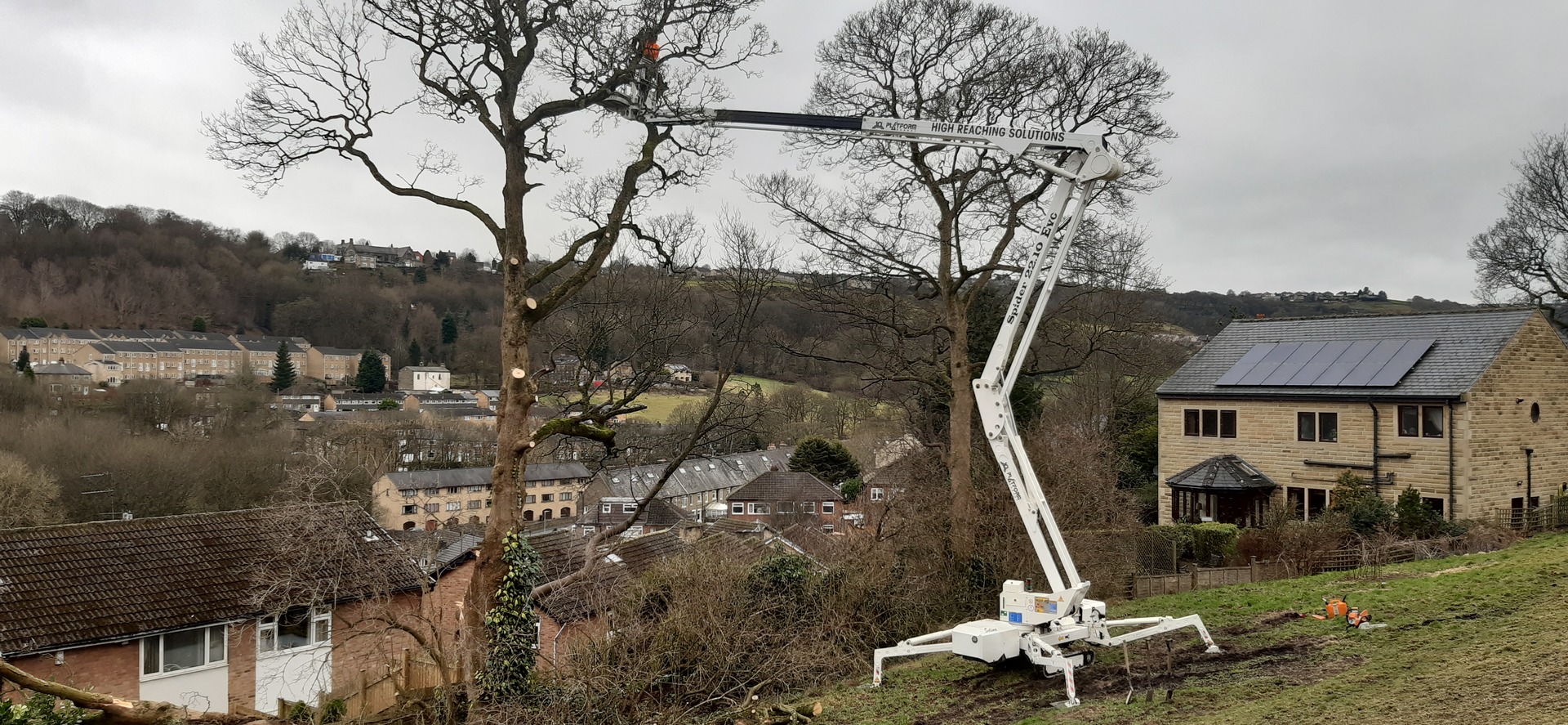 Selina, High Reaching Solutions 22m Lithium hybrid tracked spiderlift cherrypicker, set-up on steep grass bank and boomed fully out assisting an arborist to dismantle a dangerous storm damaged tree near Halifax.